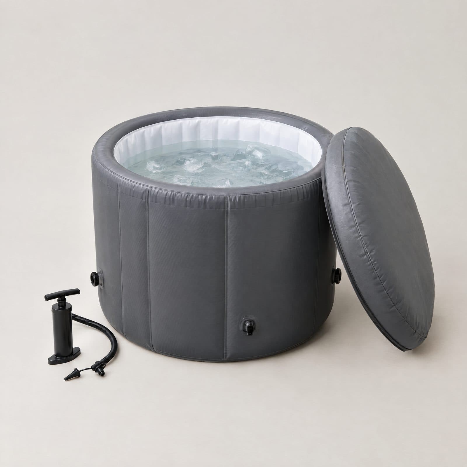 Bain froid tonneau gonflable gris orage rempli d'eau claire et de glaçons, son couvercle isotherme posé contre lui, sur fond gris clair